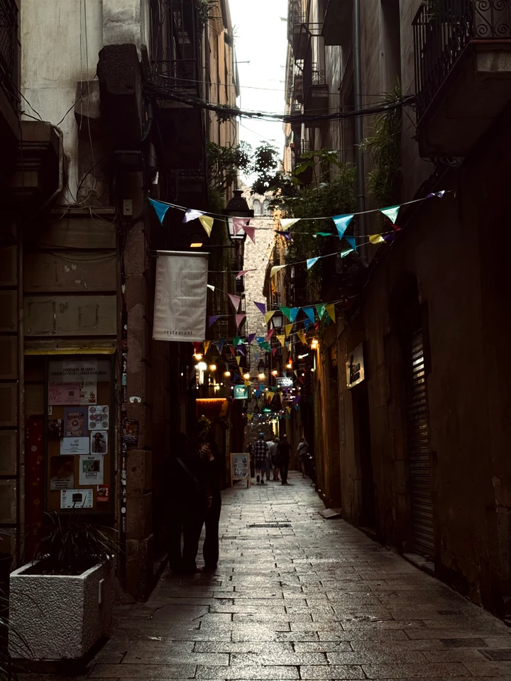 Guirlandes de fanions colorés suspendues entre les façades d’une ruelle pavée.