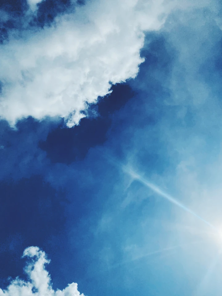 Nuages blancs ouverts sur un ciel bleu traversé par de fines traînées.