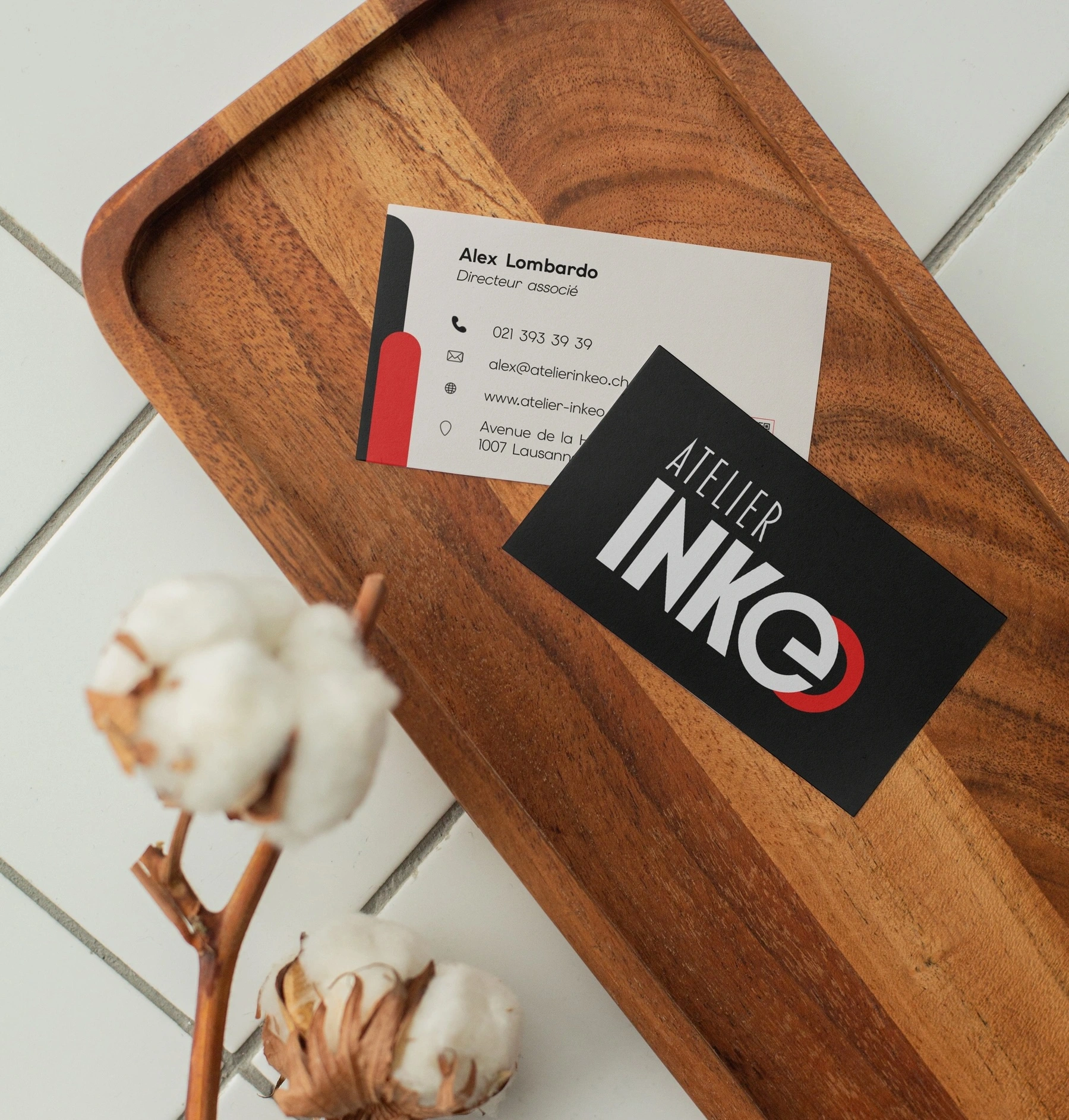 Recto et verso de la carte de visite Atelier Inkéo, mis en situation sur un plateau en bois.