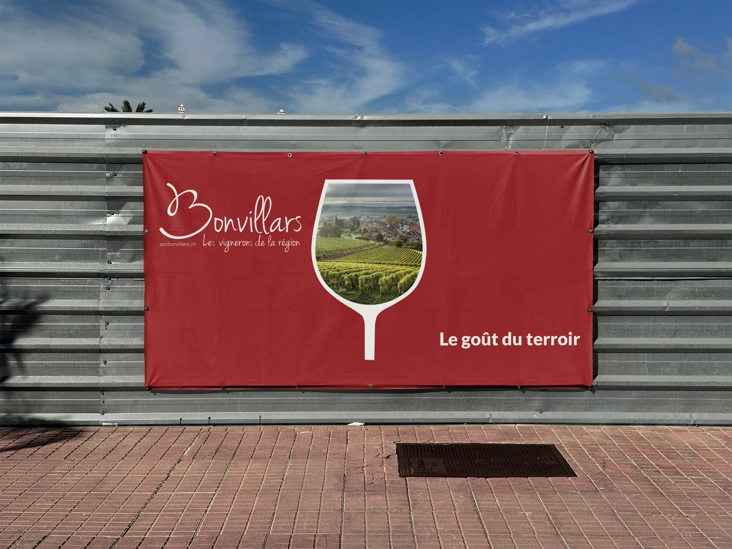 Mise en situation de la bâche rouge avec le verre et le vignoble.